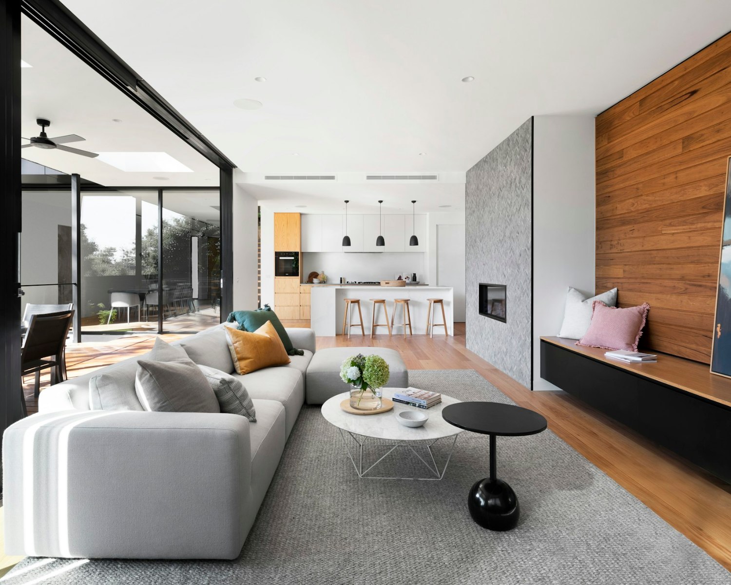 Sala integrada com cozinha, ilha de pedra clara e painel de madeira