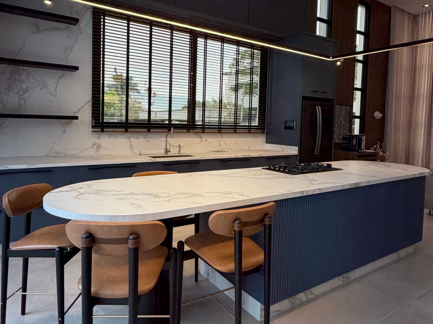 Ilha de cozinha com mesa oval de mármore branco e banquetas